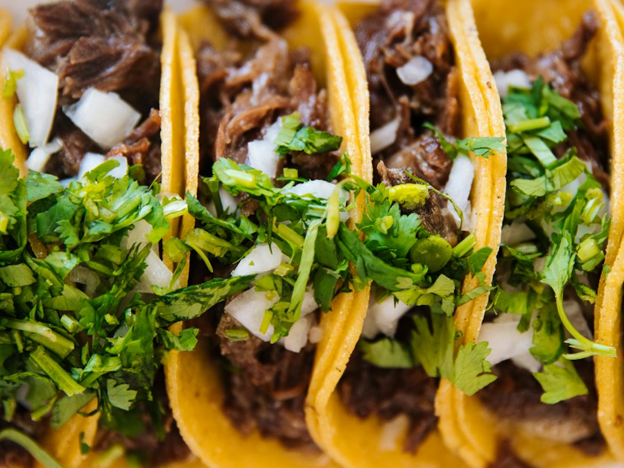 Three beef tacos topped with chopped onion and cilantro