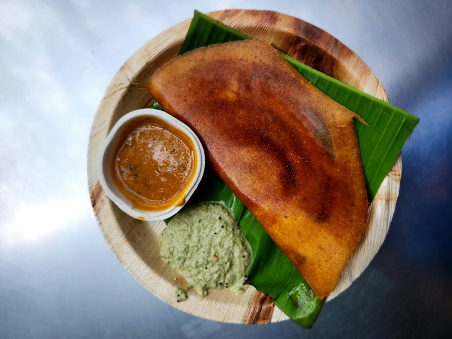 Crispy dosa with coconut chutney and sambar on a banana leaf