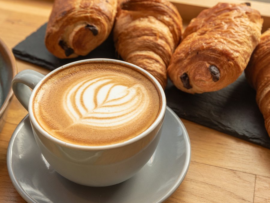 Latte with latte art beside fresh croissants