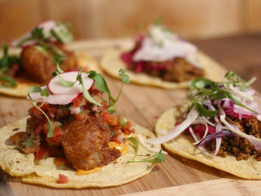 Four battered fish tacos on a tray
