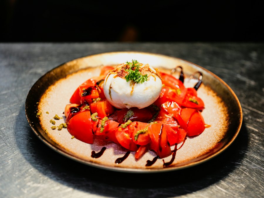 Burrata with tomatoes, pesto and balsamic on a wooden table