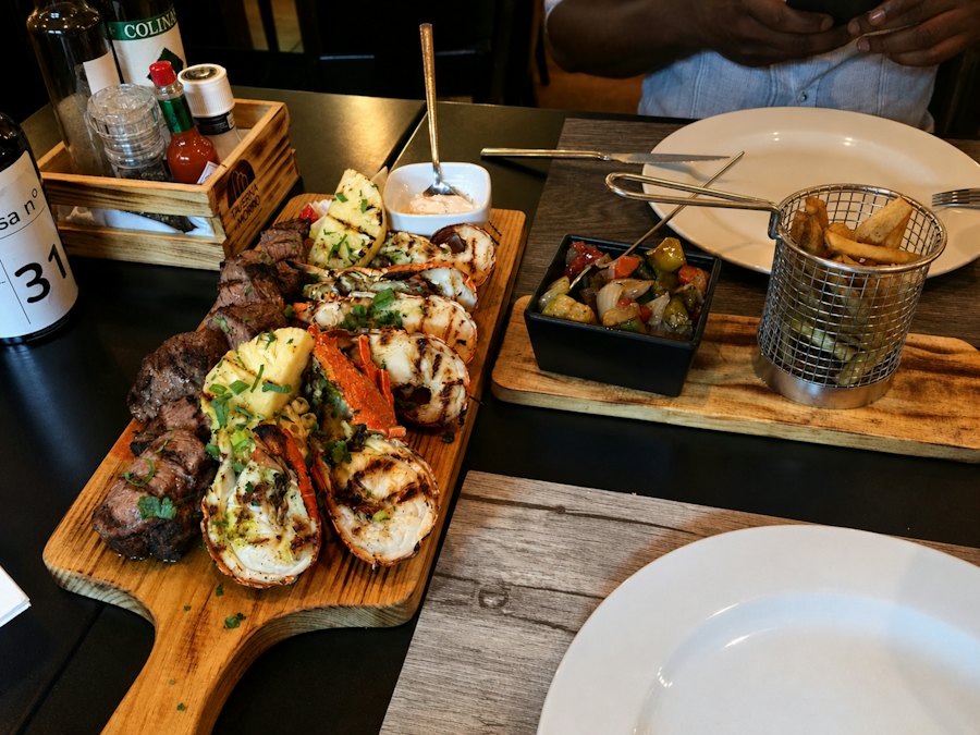 Grilled steak and lobster surf and turf on a wooden board with fries