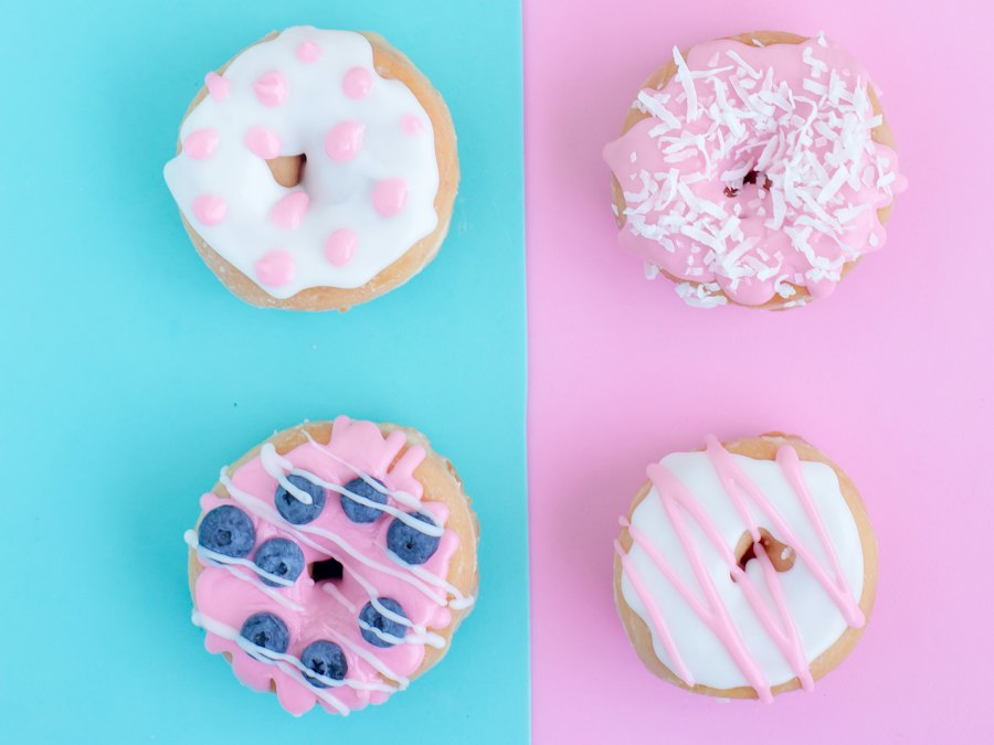 Six assorted glazed doughnuts on a pastel background