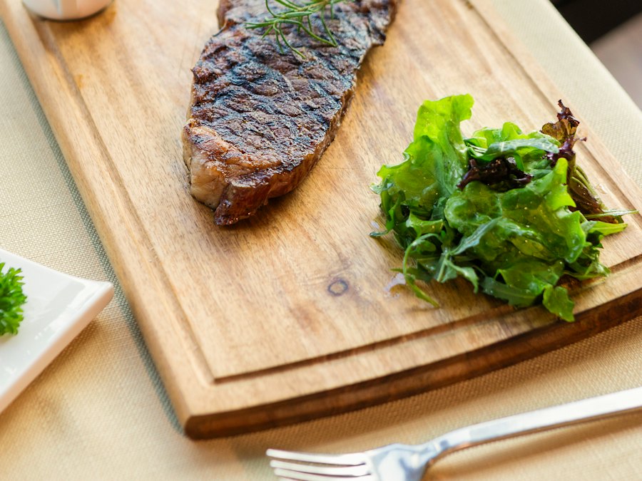 Grilled ribeye steak with roasted vegetables on a wooden board