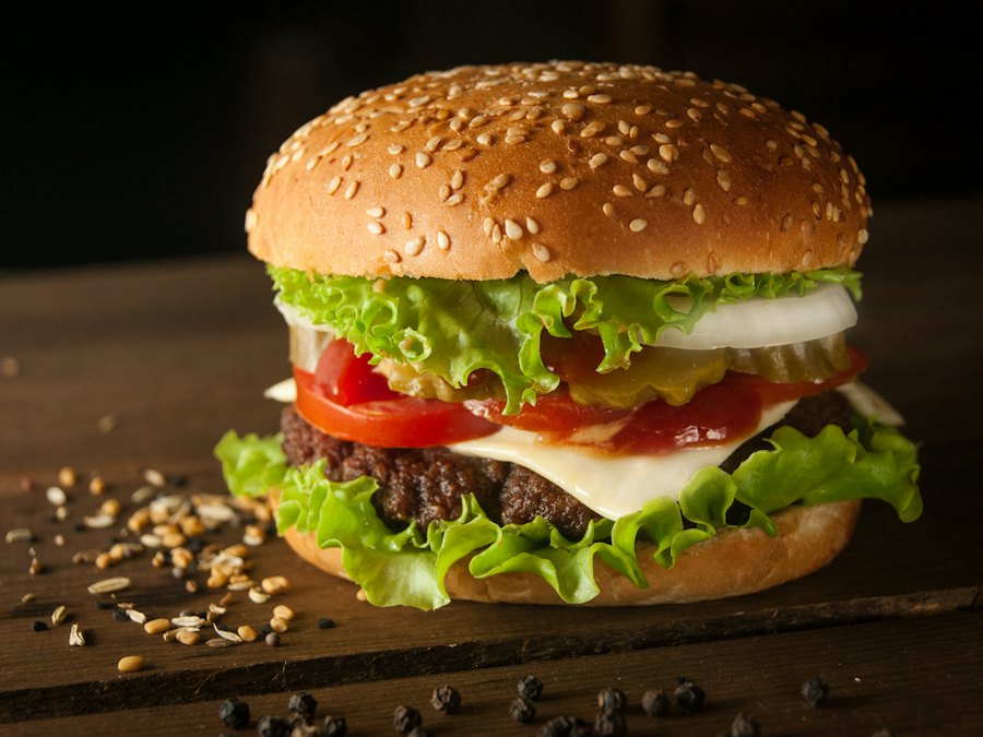 Cheeseburger with lettuce, tomato and onion on a dark wooden table