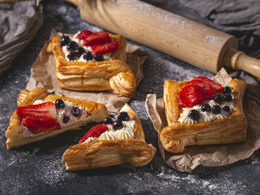 Four pastries topped with strawberries and blueberries